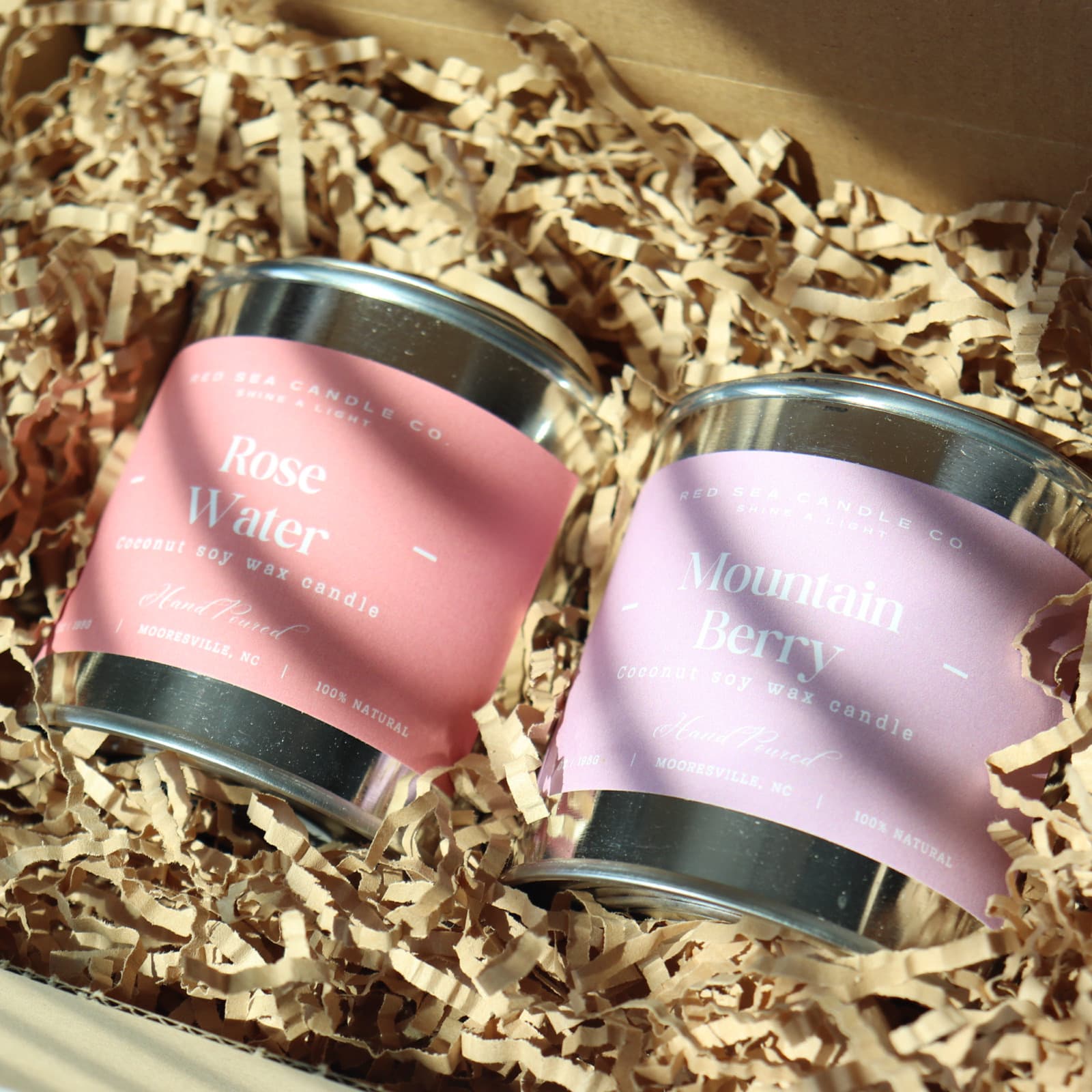 The Red Sea Candle Co. Gift Box with a Rose Water and a Mountain Berry tin nestled in crinkle paper
